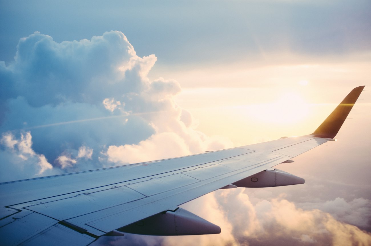 An aircraft wing above sunlit clouds